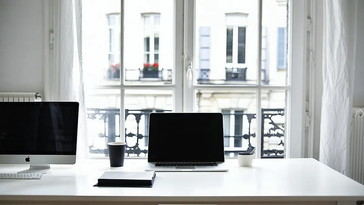Atmospheric Paris workspace — architectural overhead view of a minimal desk with laptop and notebook, soft natural light